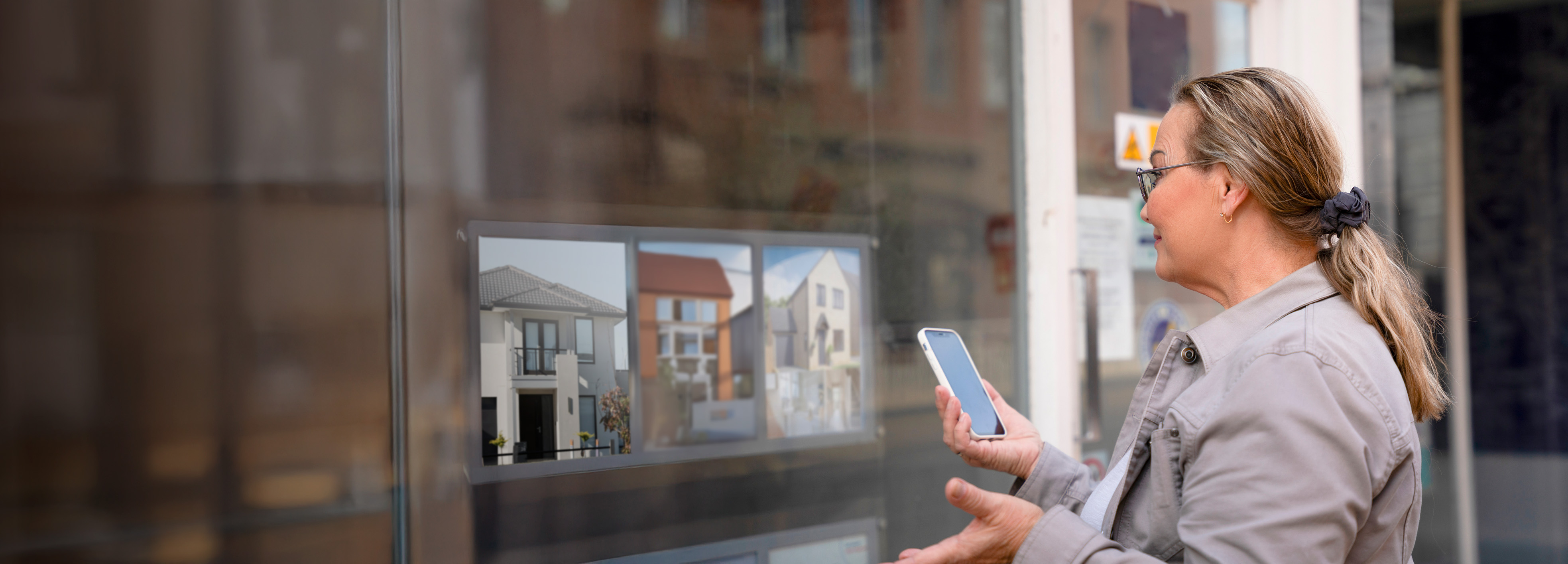 Person standing in front of real estate office looking in at available residences