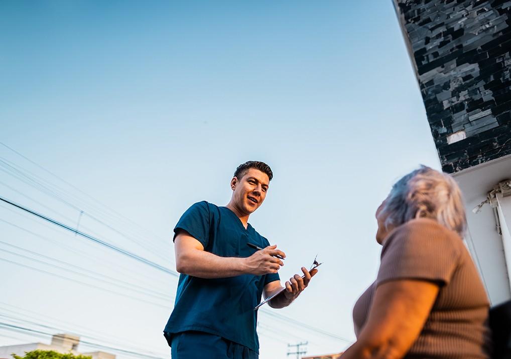 A healthcare worker speaking to an elderly woman