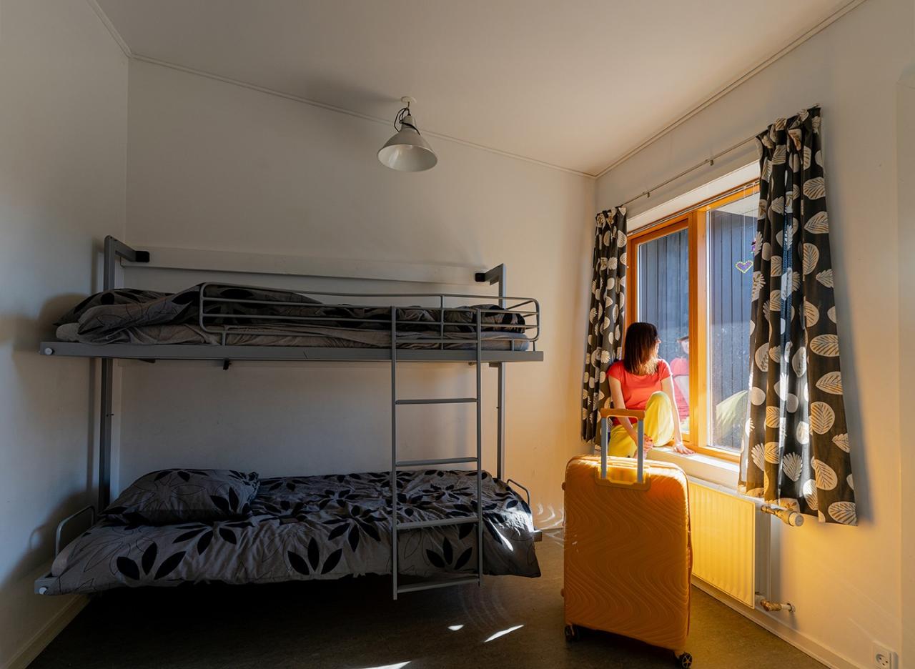 Small room with bunk beds. A woman is sitting at the windowsill looking out the window