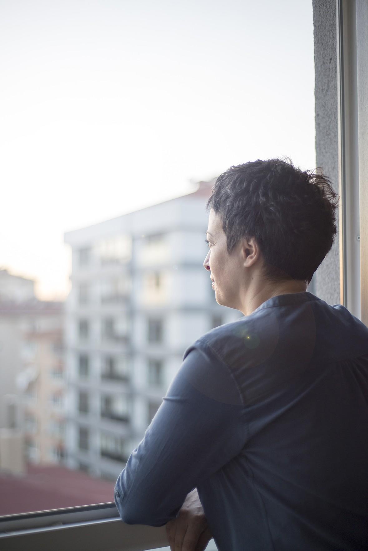 Woman standing at a window looking out at a city view