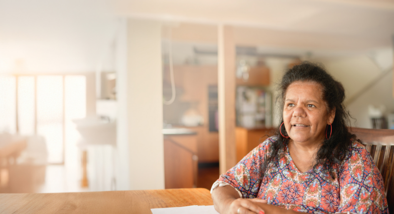 First Nations woman sitting at table in a house, smiling ahead
