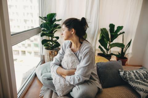 Woman looking out window in apartment