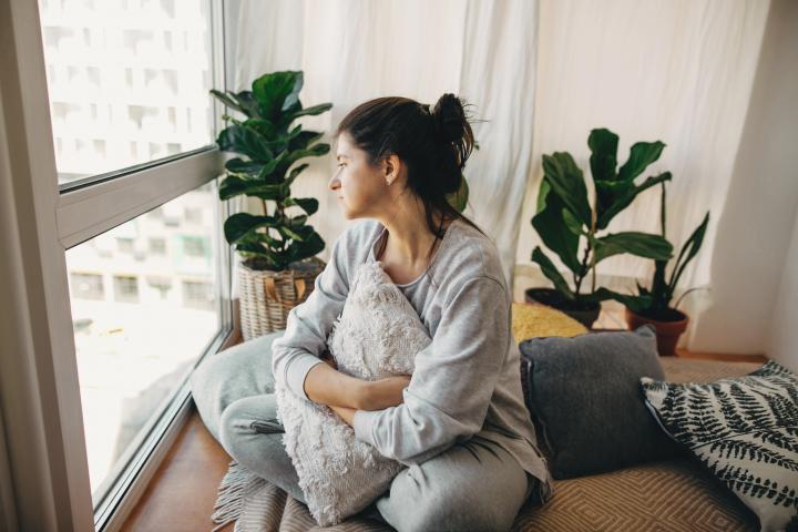 Woman looking out window in apartment