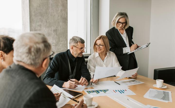 Business professionals sitting around a table discussing data on printouts