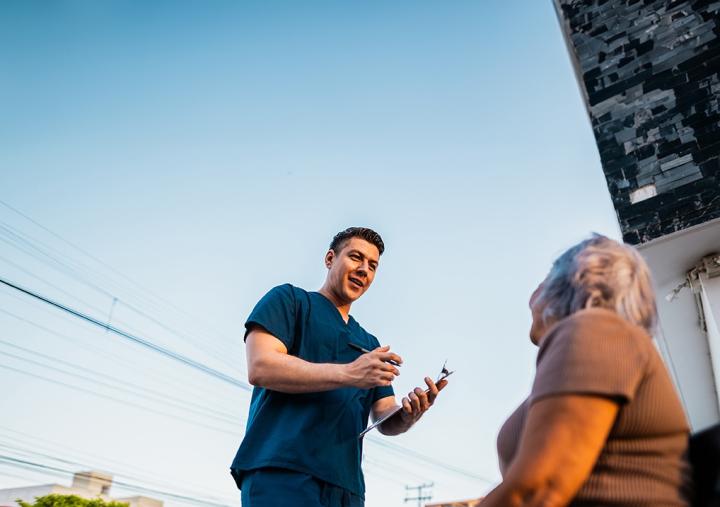 A healthcare worker speaking to an elderly woman