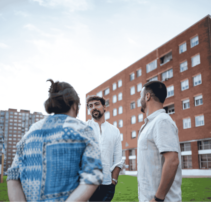 3 men standing together talking outside an apartment building