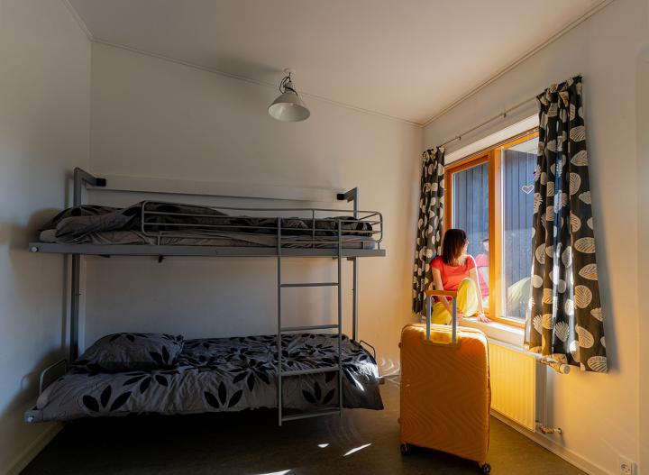 Small room with bunk beds. A woman is sitting at the windowsill looking out the window