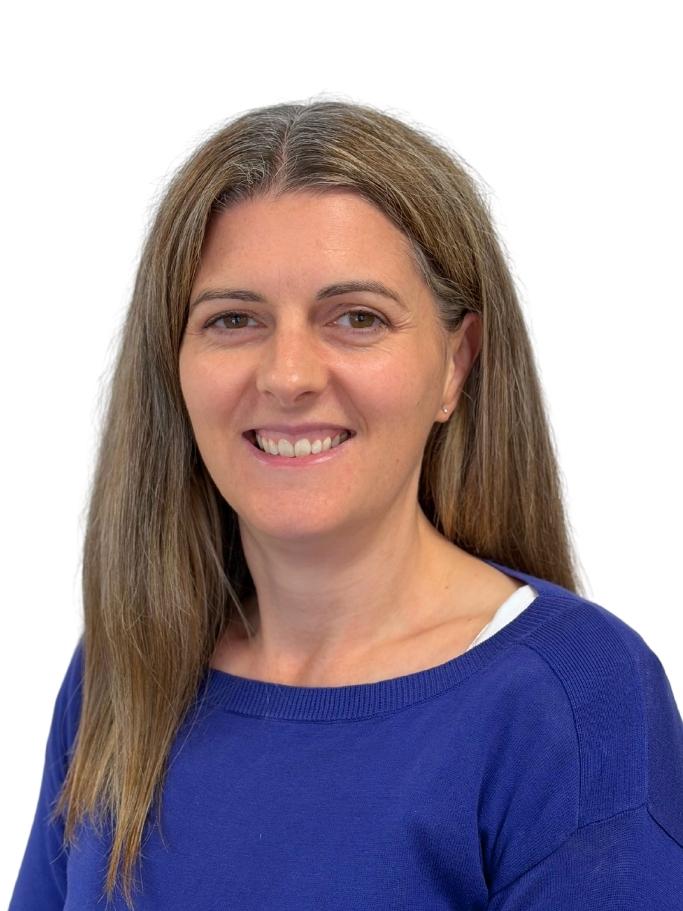 Headshot of Megan Robinson. She has long brown hair and is wearing a blue jumper.