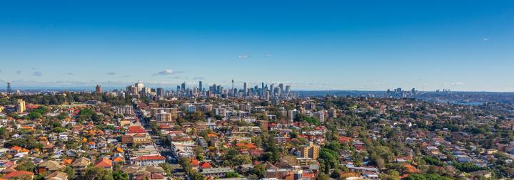 Birds eye of Australian city, with suburbs in foreground, extending to a city skyline and blue skies