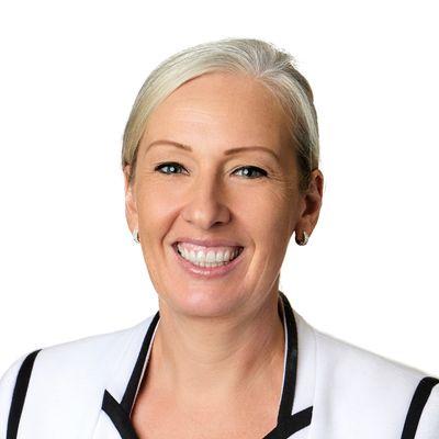 Photo of Jennifer Garbett. She has blonde hair that is tied back and is wearing a white jacket with black trim.