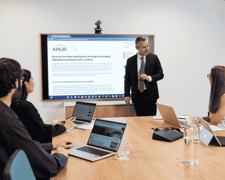 Group photo of AHURI Professional Services team members conversing in a conference room