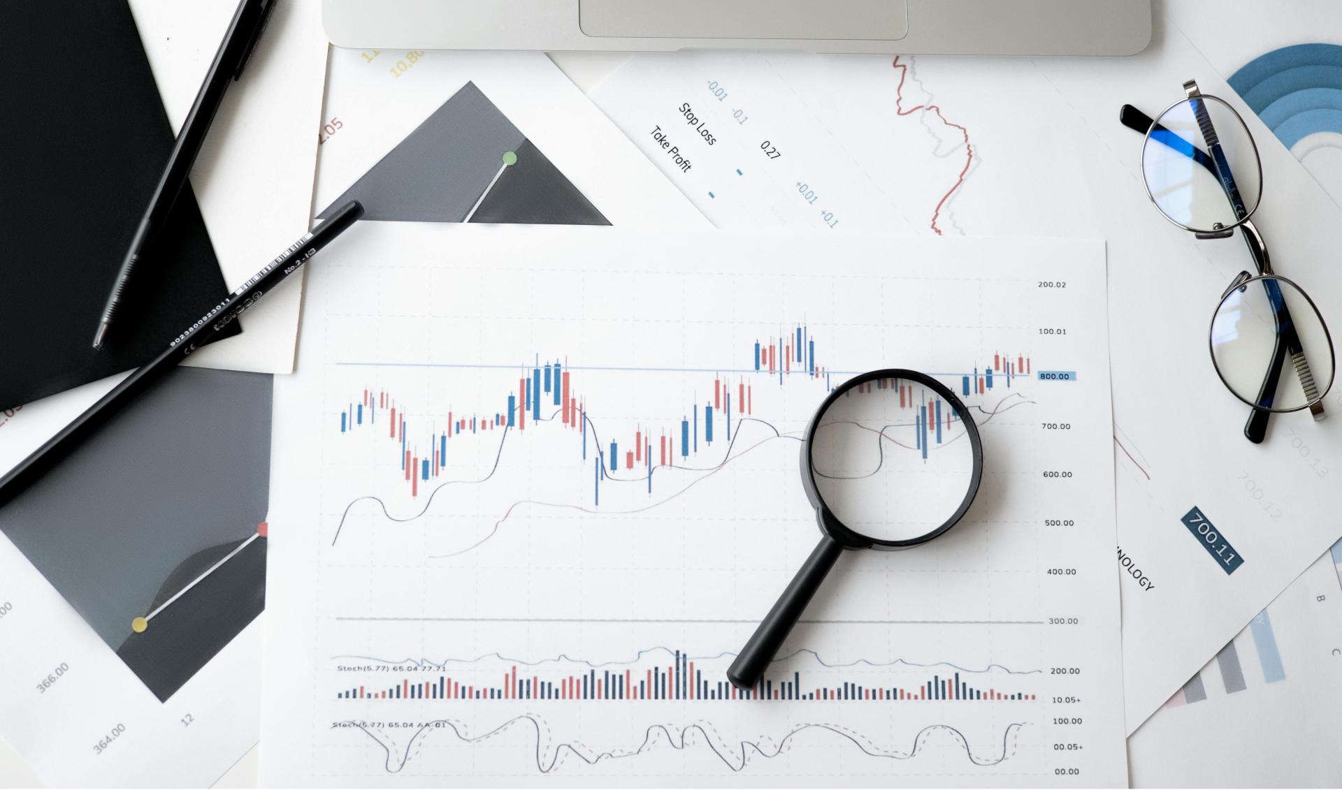 Collection of papers with graphs and data with a magnifying glass resting on top