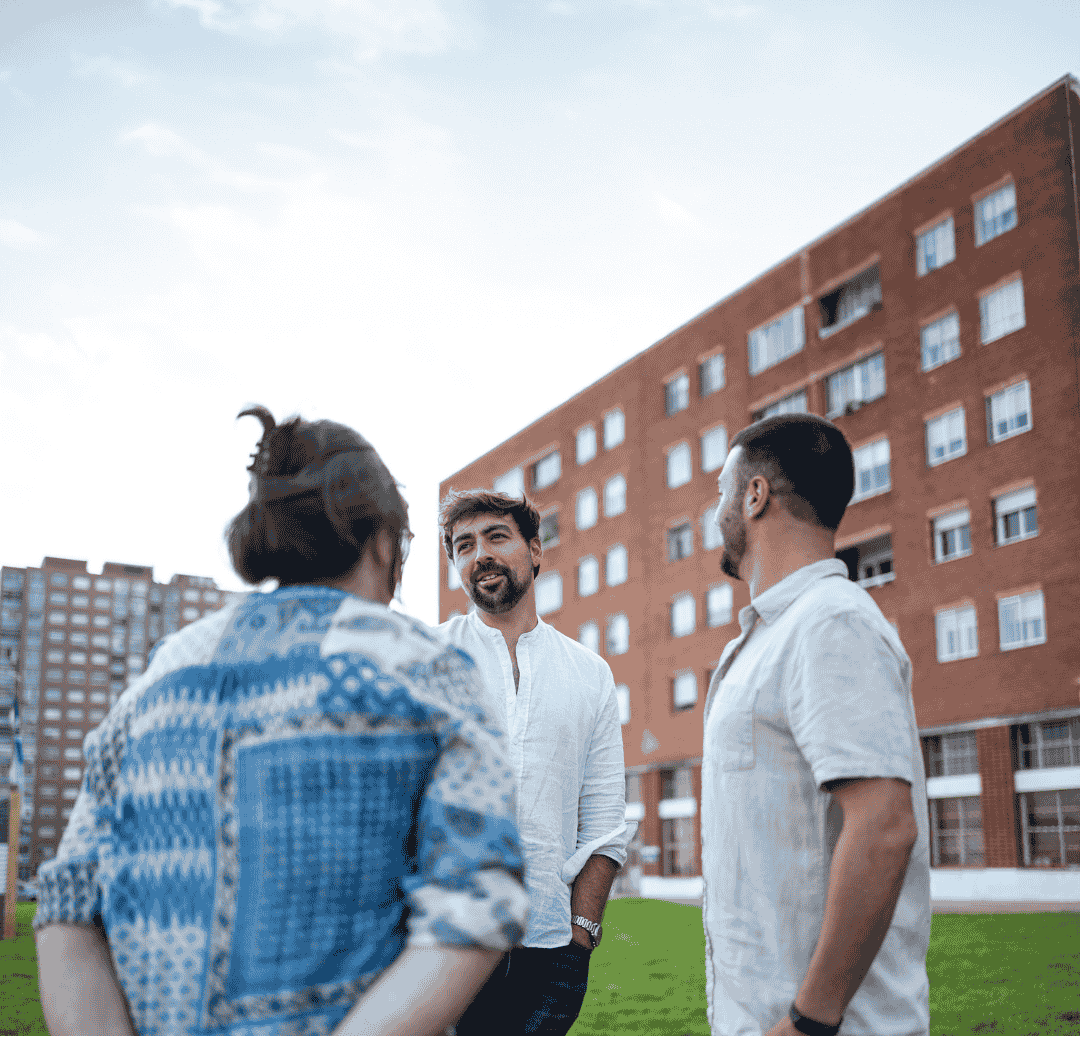 3 men standing together talking outside an apartment building
