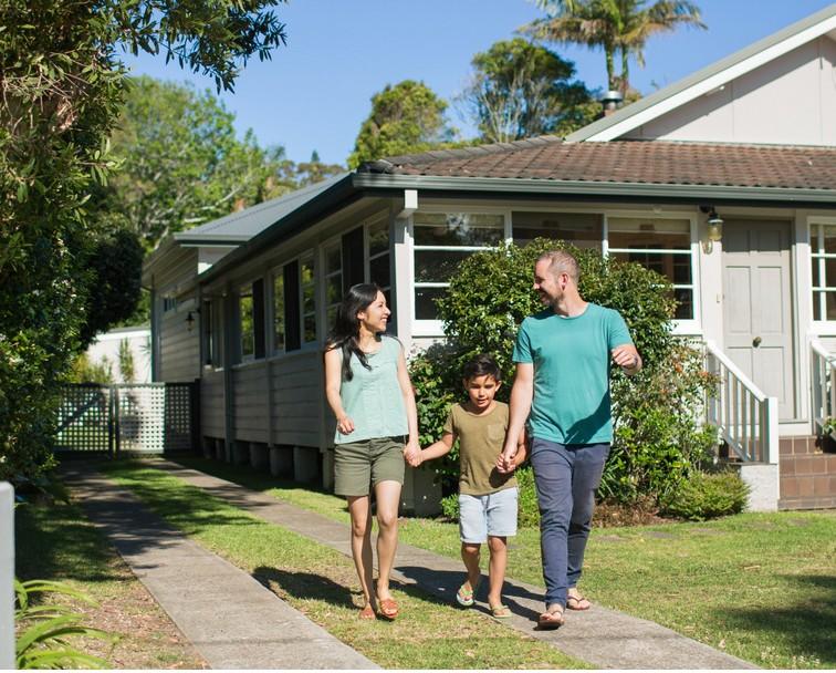 Parents and child walking up the driveway while smiling and holding hands