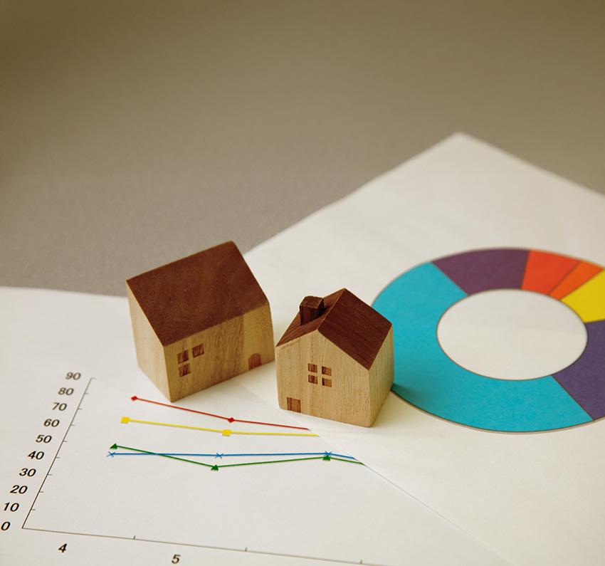 Two small wooden houses sitting on papers with colourful graphs