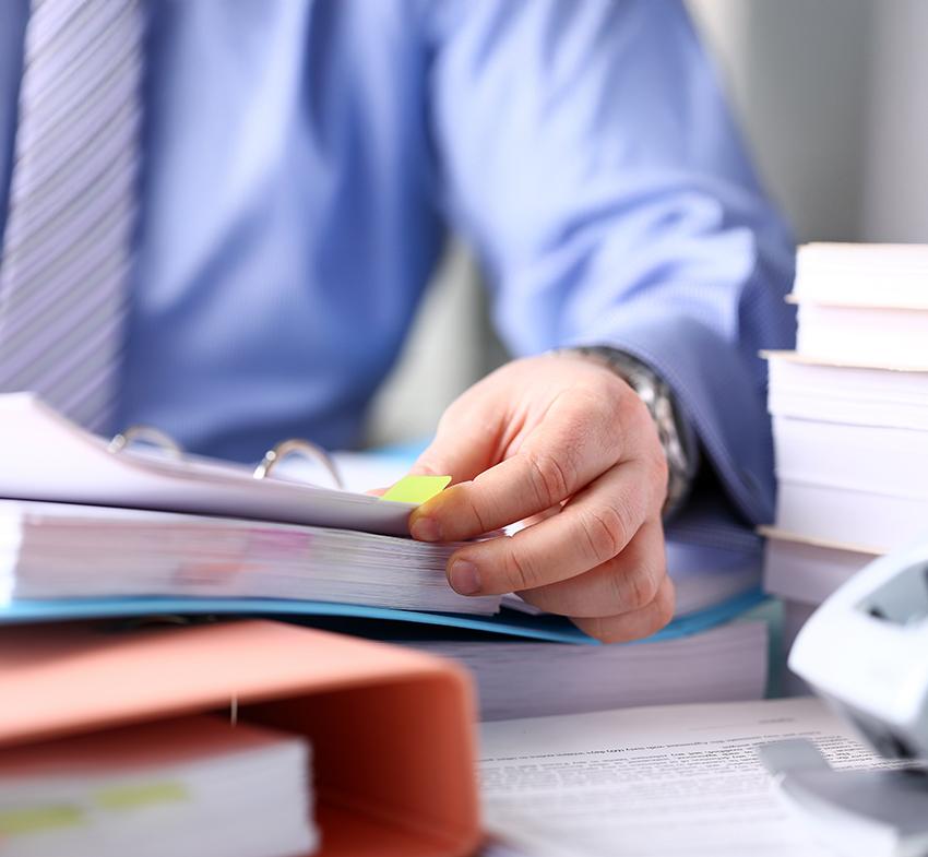 Close up of businessman sitting at desk flicking through a binder of documents