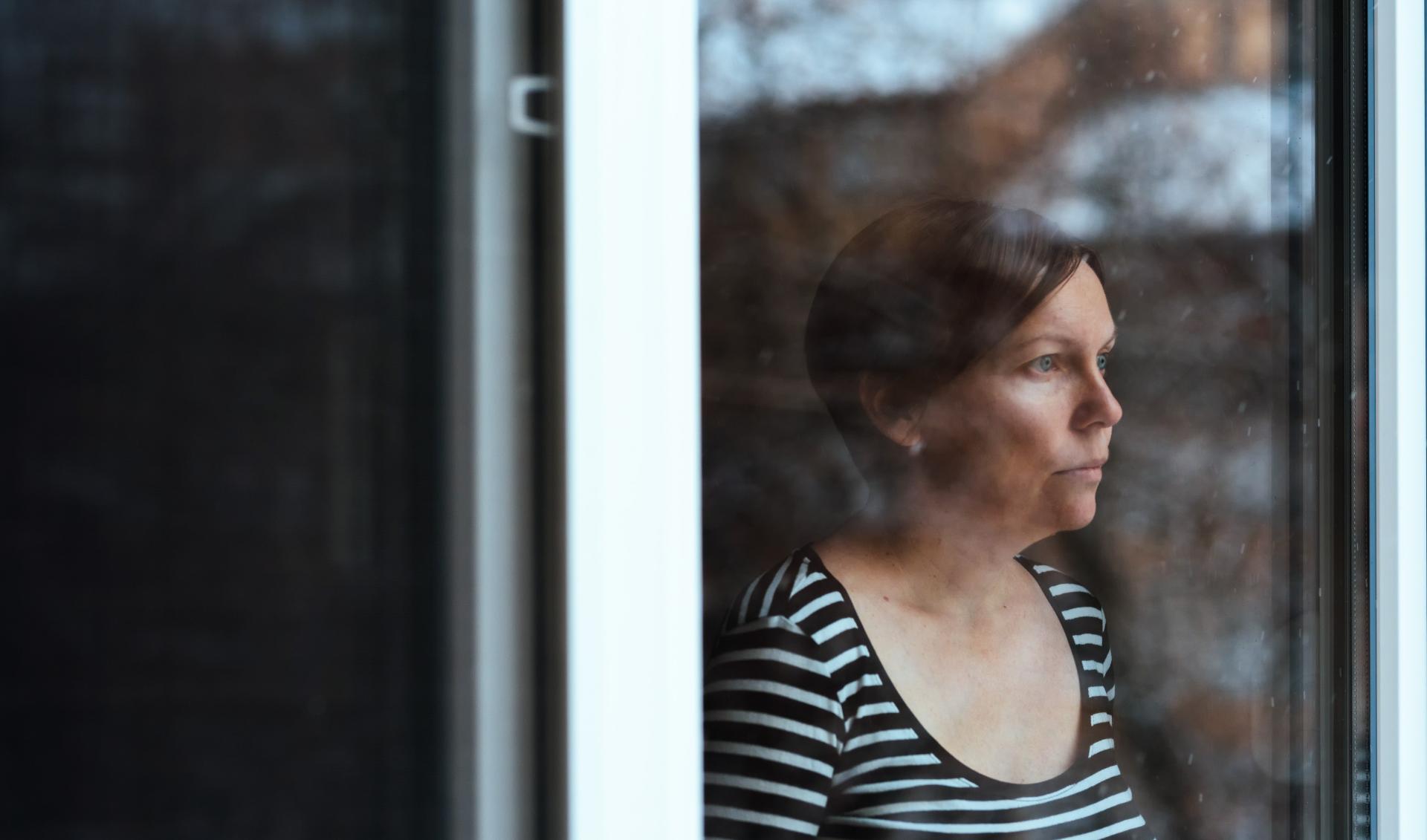 Woman looking out of window onto dark weather