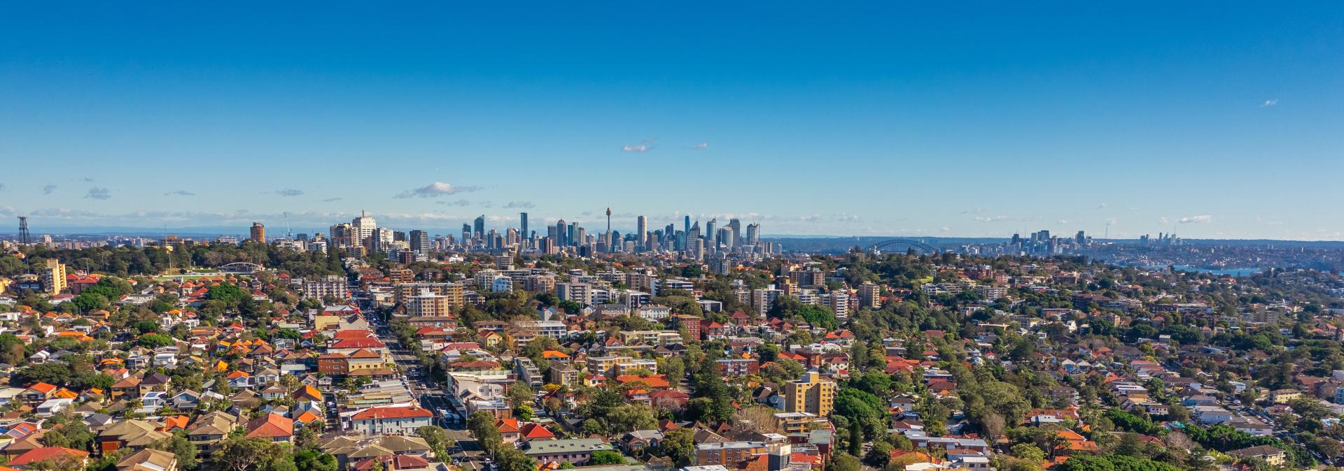 Birds eye of Australian city, with suburbs in foreground, extending to a city skyline and blue skies