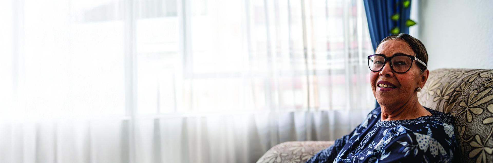 Woman sitting on couch smiling toward the camera