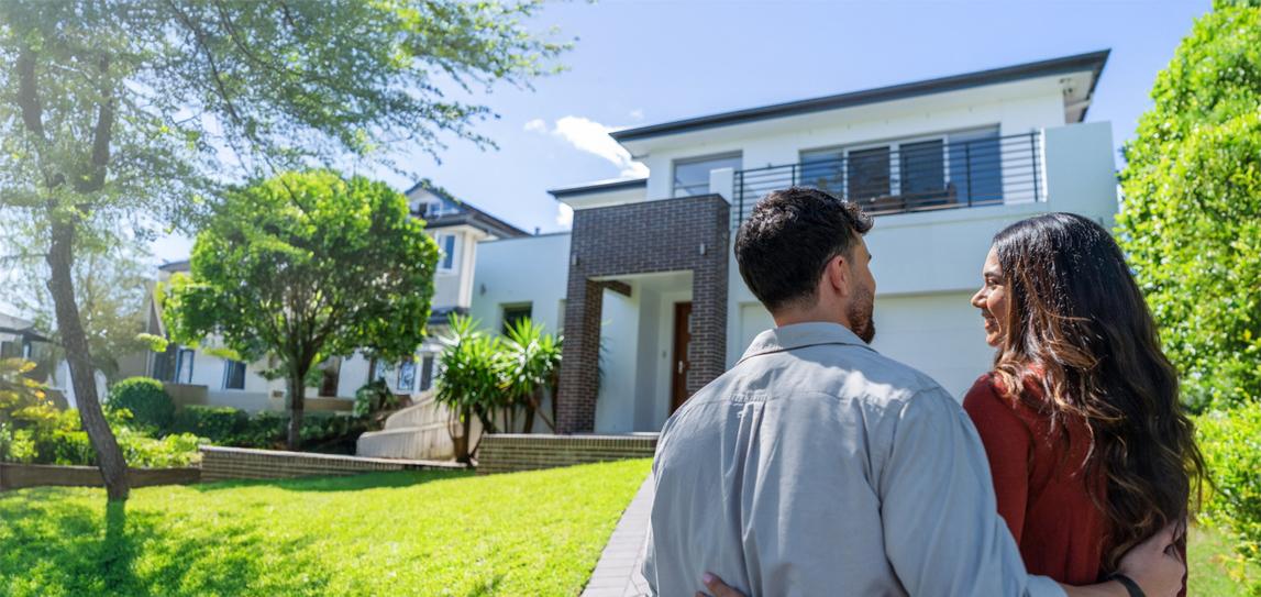 A young couple standing in the driveway of a suburban house