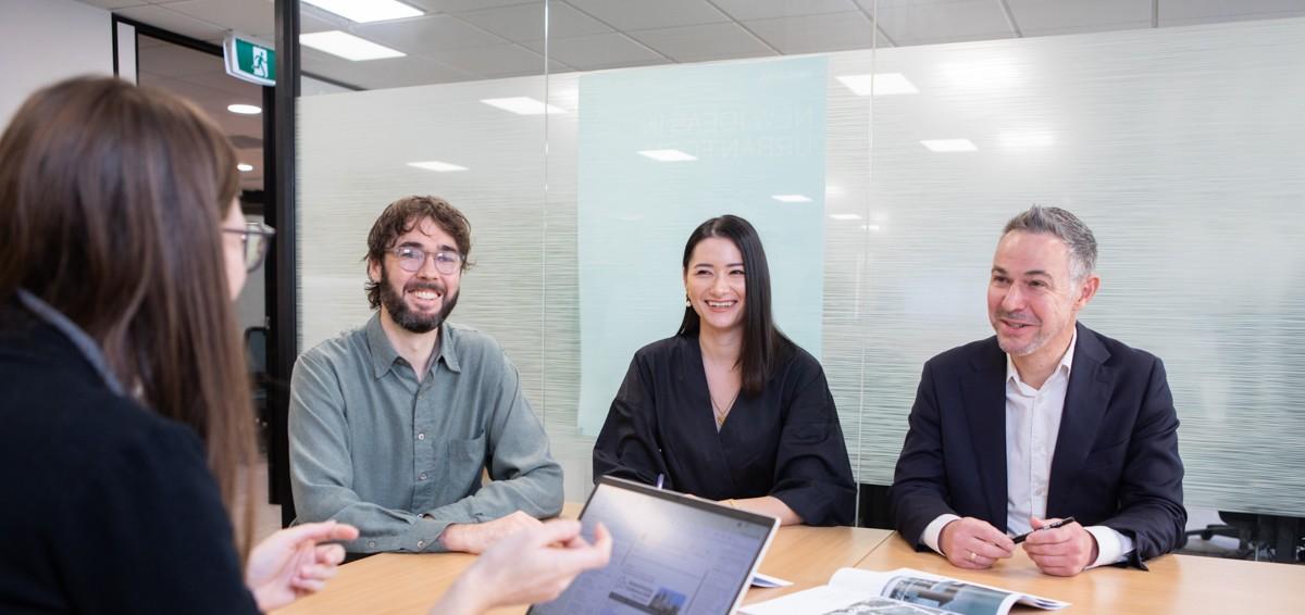 Group photo of AHURI Professional Services team sitting in office at desk
